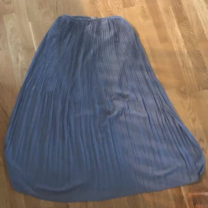 Kjol - Lång kjol i medium. Helt oanvänd efter ett felköp. Blå i polyester med veck betala själv för frakt. Nypris 400