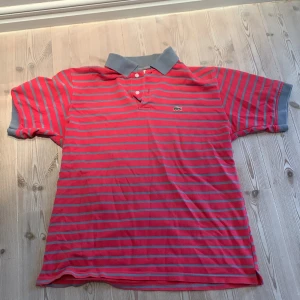 Lacoste Polo - Grå, Rosa randig Polo skjorta från Lacoste, väldigt bra skick!