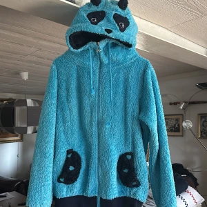 Blå panda tröja/hoodie - Säljer denna tröja/hoodie. Jag köpte den på Öland för ett par år sedan men har växt ut den. Den är både mjuk och mysig att ha på sig. katt finns i hemmet