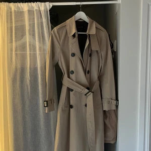 Trenchcoat - Supersnygg trenchcoat, knappt använd och i skick som ny! Köptes för ca 1,5 år sedan men användes it tillräckligt så jag känner att den blir mer till användning hos någon annan. Köpt för ca 1700kr på massimo dutti Defekt: hål i ena fickan, syns ej