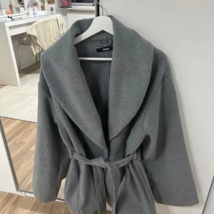 Kappa  - Grå kappa i medellängd i storlek Xl. Aldrig använt 