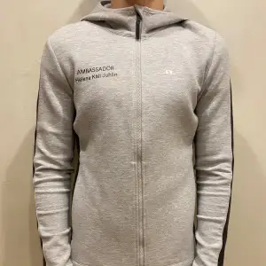 Hoodie J.Lindeberg  Modell: 184cm & väger 84kg  Skick: allmänt använd, lite missfärgat på ena armen  Färg: grå Material: polyester, viskos, elastan 