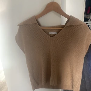 Beige tröja utan armar  - En beige aktiv stickad tröja från STOCKHOLM LM i storlek s. Den är mer Som en T-shirt utan några Armar. 