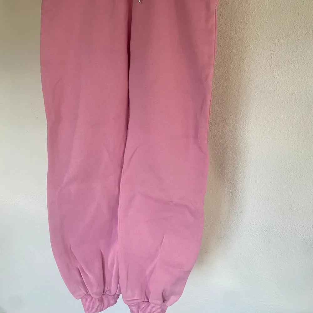 Mjukisbyxor i sweatshirt-material i rosa från NLY Trend (Nelly.com). En ”oversize” modell med resår samt dragsko i midjan och två fickor framtill. Ribbad mudd i midjan samt benslut. Fint skick.. Jeans & Byxor.
