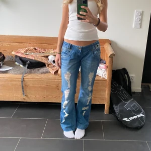 Lågmidjade bootcut jeans - Säljer dessa lågmidjade utsvängda jeans med slitna detaljer därfram❤️‍🔥 Midjemått: 42 cm