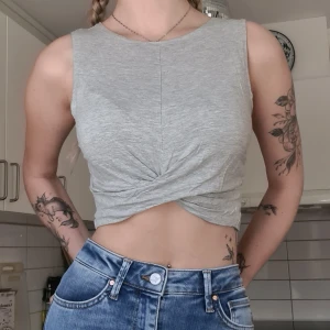 Grå croptop - Grå croptop, snurrad framtill, jätteskönt tyg. Använd men i fint skick, normal i storleken. Funkar till både S och XS. Kom med prisförslag😊  Material: 92% Viskos, 8% Elastan. 