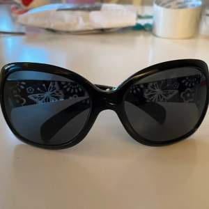 Svarta solglasögon med mönster på sidorna 