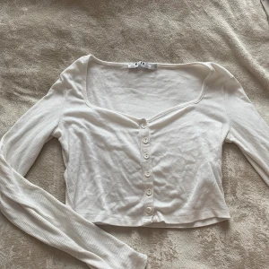 Hjärtformad top - Långärmad, cropped, hjärtformad topp som även kan användas som kofta. Tunt material i en kall vit färg. Är i storlek 36 men passar även en 38 pga det stretchiga materialet. 