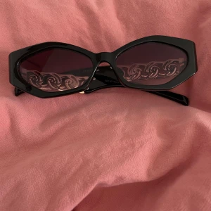 Svarta solglasögon med gulddetaljer - Ett par eleganta svarta solglasögon med mörka linser och gulddetaljer på bågarna. Säljs i fint skick. 🖤