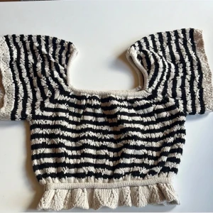 Randig topp - Söt och bekväm topp i svart och beige med ränder i storlek s. Toppen har korta ärmar och en spetsad kant längst ner. Använts ett fåtal gånger så den är i fint skick.