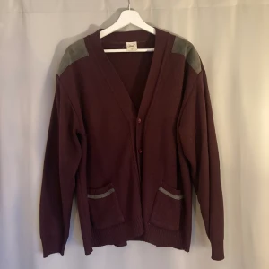 Vintage Cardigan / Kofta Storlek Large - En get vinröd cardigan med detaljer i grått mocka tyg. Storleken på tvättlappen säger 52, så passar ungefär som en vanlig storlek large.
