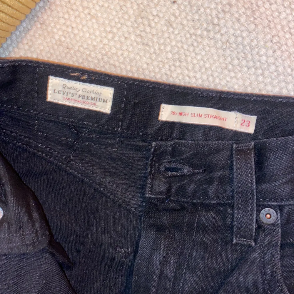 Svarta Levis jeans i modellen 70s High Slim Straight. Storleken är Waist 23 Lenght 31. Urtvättade svarta med uppklipps slits på insida ben/fot. Längden på byxbenet mätt från skrevet: 79-80 cm. Jeans & Byxor.