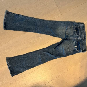 Blå jeans med knappar på bakfickorna - Fint skick, knappt använda.