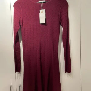 Snygg klänning  - Maskinstickad klänning med markerad midja och lite klockad kjol. Går till strax ovan knät. 