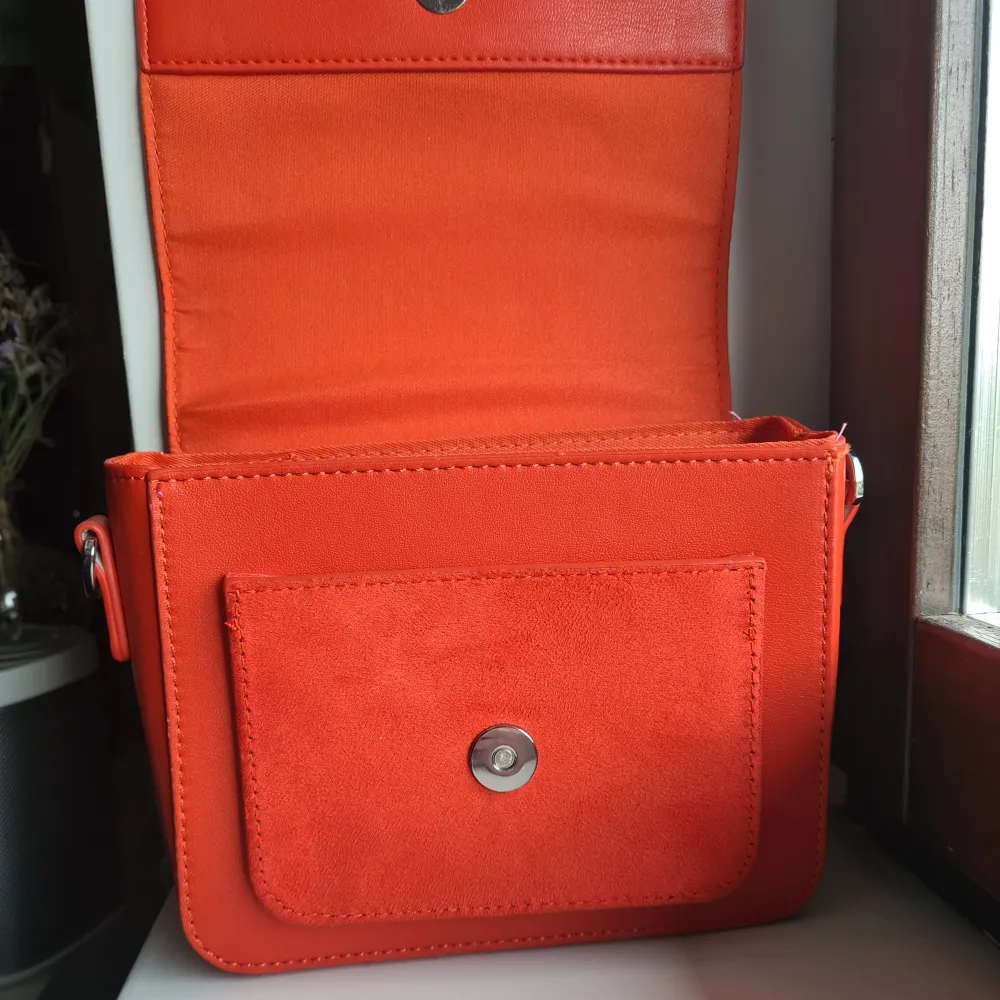 Nästintill oanvänd Carin Wester 'Cynthia' handväska i en färgstärk orange-röd nyans. Rämmen är ljusterbar samt går att ta av. Mått - Bredd: 19 cm. Höjd: 14 cm. Djup: 7 cm. Dropplängd: ca 50 cm. Bredd axelrem: 3,5 cm. Nypris 499 kr (Åhléns) . Väskor.