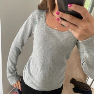 Grå långärmad topp - Grå längärmad tröja med broderi över axeln. Köpt second hand, storlek s