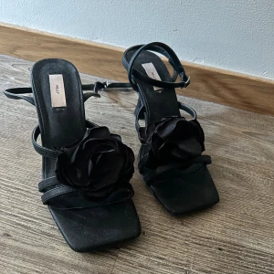 Klackar med rosettdetalj - Snygga svarta klackar från Nelly med rosettdetalj. Perfekta för festliga tillfällen.