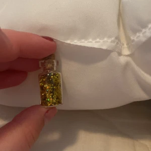 Guldglittrig ögonskugga i burk - En liten burk med guldglittrig ögonskugga. Perfekt för att lägga till en glittrande effekt på ögonlocken.