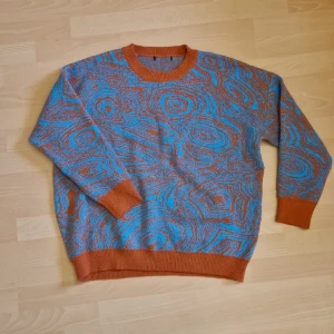 Stickad tröja - Jättemysig stickad tröja i polyester, supermjuk! Med mönster i blått och orange.   Köpt på plick men aldrig använd, då jag inte var helt nöjd med passformen på mig.   Står ingen storlek, men skulle säga M.