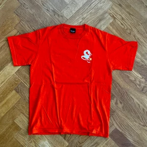 Stussy t-shirt orange - Vintage Stussy t-shirt i orange med grymt coolt tryck. Storlek M. 