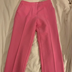 Rosa kostymbyxor från NAKD - Rosa kostymbyxor från NAKD i storlek 38. Bara använda en gång så de är i bra skick. Det är ganska långa! Går ner till marken på mig som är 175! Det är bara att ställa frågor om ni har några. 
