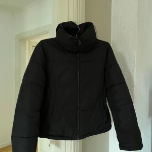 Svart pufferjacka - En svart pufferjacka från Bikbok, strl S. Ganska kort i modellen. Lite sminkfläckar på insidan av kragen. Fyllningen har flyttat sig lite på insidan men går nog att fixa någorlunda med enkla medel. Hör av er vid frågor!  😊 Frakt inkluderad i priset.