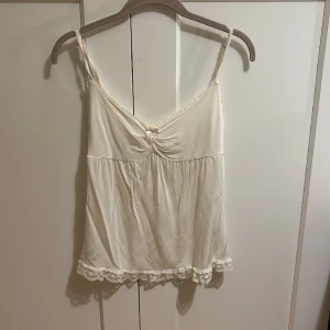 Vitt spetslinne med rosett - Säljer eftersom det inte kommer till användning. Vet ej vilken storlek men passar ungefär XS till M. 