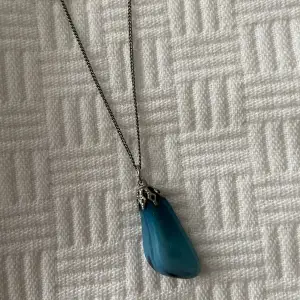 Ett halsband i silver med en blå sten 💙Är ganska säker på att det är en äkta kristall, en blå agat! Köpte den på loppis och har frågat runt lite och de flesta tror den är äkta 🥰Ingen garanti dock, riktigt snygg oavsett! Lite indie-goth stil 🖤