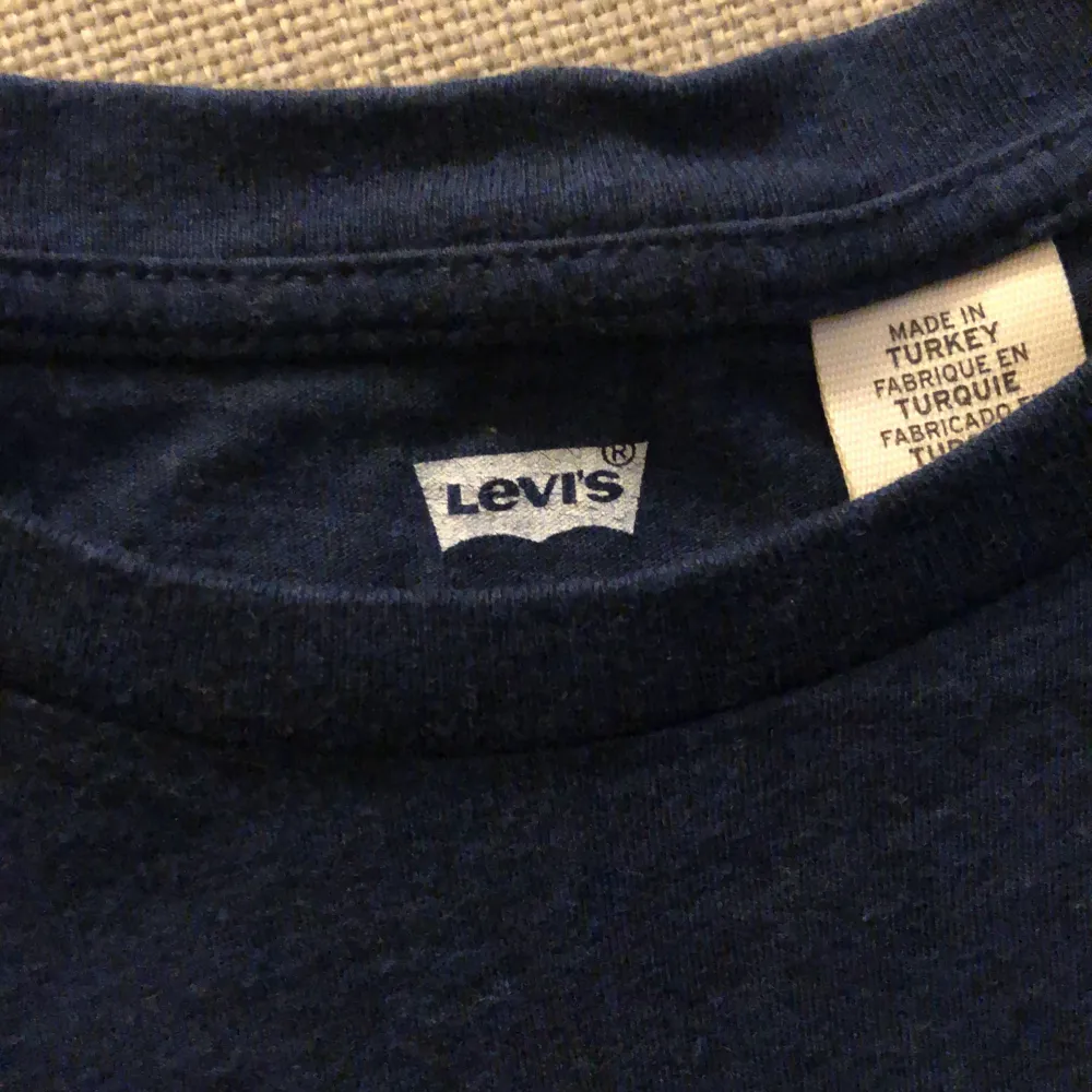 En mörkblå t-shirt från Levi's med korta ärmar och en tryckt logotyp i vitt, rött och blått på framsidan. T-shirten är tillverkad i Turkiet.. T-shirts.