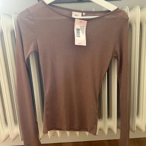Brun långärmad tröja från Nelly - En brun långärmad tröja från Nelly i nyskick. Tröjan har en enkel och stilren design med rund halsringning.