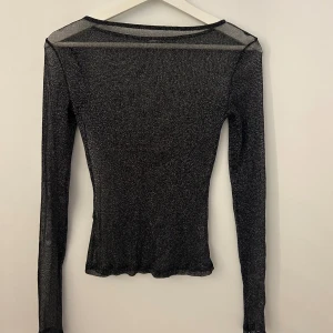 Genomskinlig glittrig topp  - Svart genomskinlig glittrig topp ifrån Nelly. Den är i storlek S