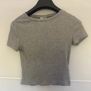 Grå ribbad topp från Divided - En grå ribbad topp från Divided med korta ärmar och rund hals. Toppen är i storlek S och har en tight passform.