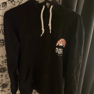 Svart hoodie från Dope Snow - Säljer en svart hoodie från Dope Snow. Den har en stor logga på bröstet med texten 'DOPE' och en cool grafisk design ovanför. Hoodien har en justerbar dragsko i vitt och en stor ficka på magen. Perfekt för höst och vinter, supermysig och stilren! 🖤