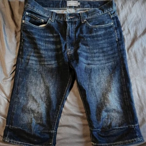 Mörkblå jeansshorts från Dressmann - Säljer ett par mörkblå jeansshorts från Dressmann i storlek S. De är i bra skick och har en klassisk design med fem fickor och dragkedja. Katt finns i hemmet, men allt jag säljer är nytvättat och rollat 💛✨