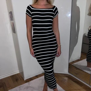 Svart och vit randig klänning från Pull&Bear - Säljer en superfin svart och vit randig klänning från Pull&Bear. Den är tight och har korta ärmar. Klänningen är ribbad och går ner till vaderna, så den är perfekt för både vardag och fest. Materialet är mjukt och stretchigt, vilket gör den väldigt bekväm att ha på sig. Passar perfekt till sommaren eller våren!