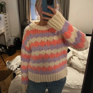 Färgglad stickad tröja - Säljer en supermysig och färgglad stickad tröja. Den har ett randigt mönster i lila, rosa och vitt. Tröjan är långärmad och har en normal passform. Perfekt för höst, vinter och sena sommarkvällar när man vill hålla sig varm och snygg! 💜🧡💗