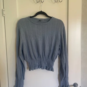 Blå croppad tröja - Säljer en superfin blå blus. Den är stickad och har långa ärmar. Tröjan har en tight passform vid midjan och är perfekt för höst och vår. Den är i bra skick och redo för en ny ägare!