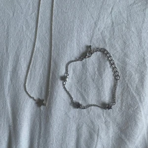 Snyggt set med halsband och armband med stjärnor - Säljer ett superfint set med halsband och armband i silverfärg. Båda smyckena har små stjärnor som detaljer, vilket ger en söt och stilren look. Perfekt för både vardag och fest! 120kr för båda elr 50 för bara armbandet o 50 för bara halsbandet