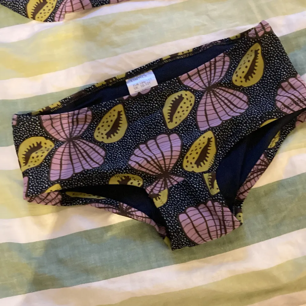 Säljer en superfin bikini från Lindex i storlek 146/152 (10-12 år). Bikinin har ett coolt mönster med blommor i rosa och gula nyanser på en svart bakgrund. Toppen har smala axelband och en volangdetalj som gör den extra söt. Perfekt för sommarens bad och strandhäng! . Muu.