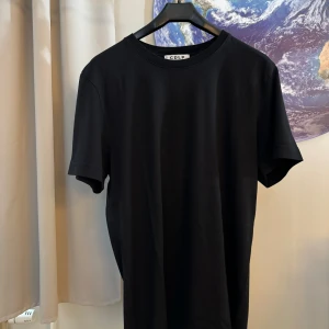 Svart t-shirt från CDLP - Säljer en stilren svart t-shirt från CDLP. Den är i nyskick och har en normal passform. Perfekt för både vardag och fest. Gjord av mjuk och skön bomull. Kortärmad och enkel design som passar till allt.