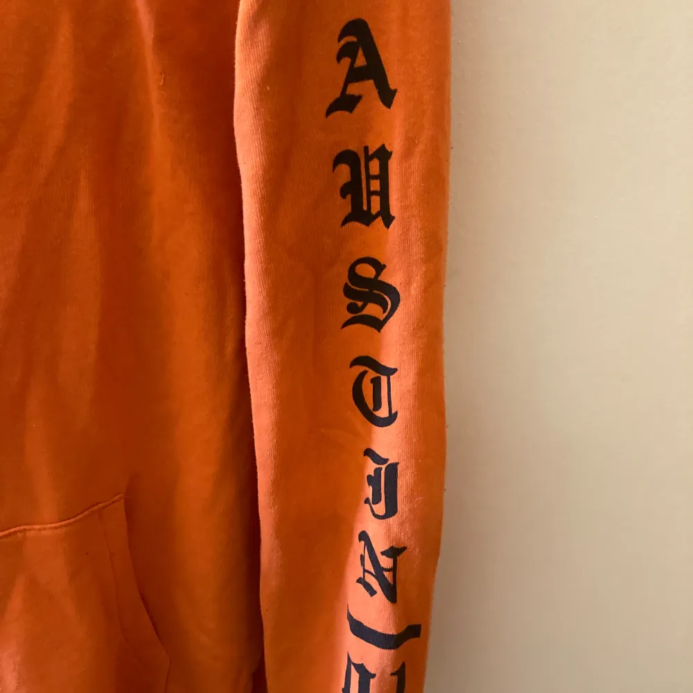 Oragne hoodie med tryck ifram och på armarna. Spegelbilden visar färgen mer korrekt. Köpte den på Plick och den är ganska använd.. Hoodies.