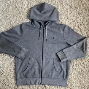 Ralph Lauren Zip - En fin Polo Ralph Lauren zip up i en lite mörkare grå färg. Tröjan är i gott skicka 8-9/10 men har två fläckar som går bort i tvätt. Den är i stolek Large och passar 180/200 cm som det står i tröjan. Skriv för fler frågor eller bilder 👌🏼