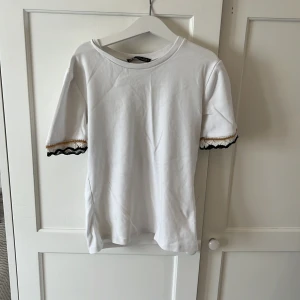 Vit t-shirt med detalj - Vit tröja från zara med broderade detaljer på änden av armen. Superbra skick och nästan aldrig andvänd. Pris går att diskutera❤️