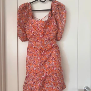 MANGO klänning med snörning i ryggen - Jättefin blommönstrad klänning med puffärm och snörning i ryggen. Kan också bäras som off shoulder. Sparsamt använd! Strl M. Passar en S-M