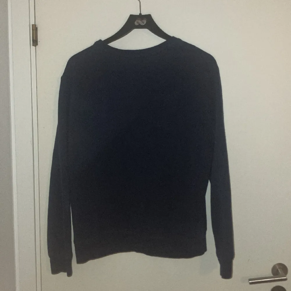 Mörkblå sweatshirt med rött märke på bröstet. Har krympt i tvätten till ungefärlig M/S storlek.. Tröjor & Koftor.