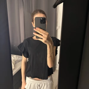 Svart volang topp - Säljer denna t-shirt med volang. Använd en del men är i fint skick, storlek S🫶🏻