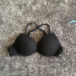 Svart pushup bikiniöverdel - Snygg svart bikiniöverdel med ett subtilt mönster och vadderade kupor. Den har justerbara axelband för perfekt passform. 