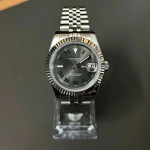 Silverfärgad klocka från Seiko - Snygg silverfärgad klocka från Seiko med romerska siffror och datumvisning. Den har en klassisk länkarmband och en stilren urtavla. Perfekt för den som gillar tidlös design.