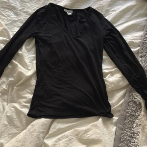 Svart långärmad v-ringad topp från Amisu - Säljer en svart långärmad topp från Amisu i storlek S. Toppen har en djup v-ringning och är tillverkad i ett mjukt och stretchigt material. Perfekt att styla till olika outfits!