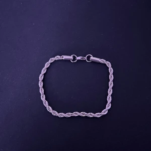 Silverfärgat armband - 18 cm. Snyggt silver armband med en elegant tvinnad design. Perfekt för att ge en stilren touch till din outfit. Armbandet har en säker låsmekanism som gör det enkelt att ta på och av.